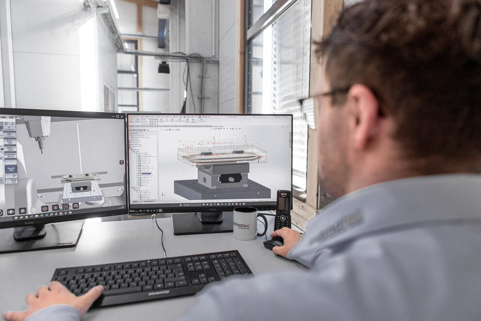 Blick über die Schulter eines Mitarbeiters auf Monitore mit CAD-Programm
